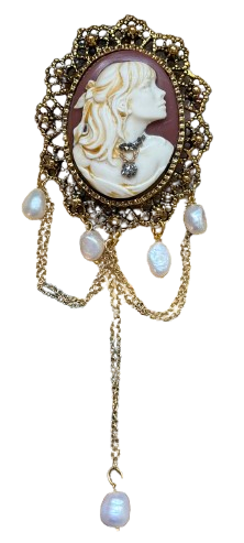 An ornate Victorian-style pendant brooch featuring a carved white cameo face with gold hair details, set in a scalloped gold filigree frame with dangling baroque pearls and chains.